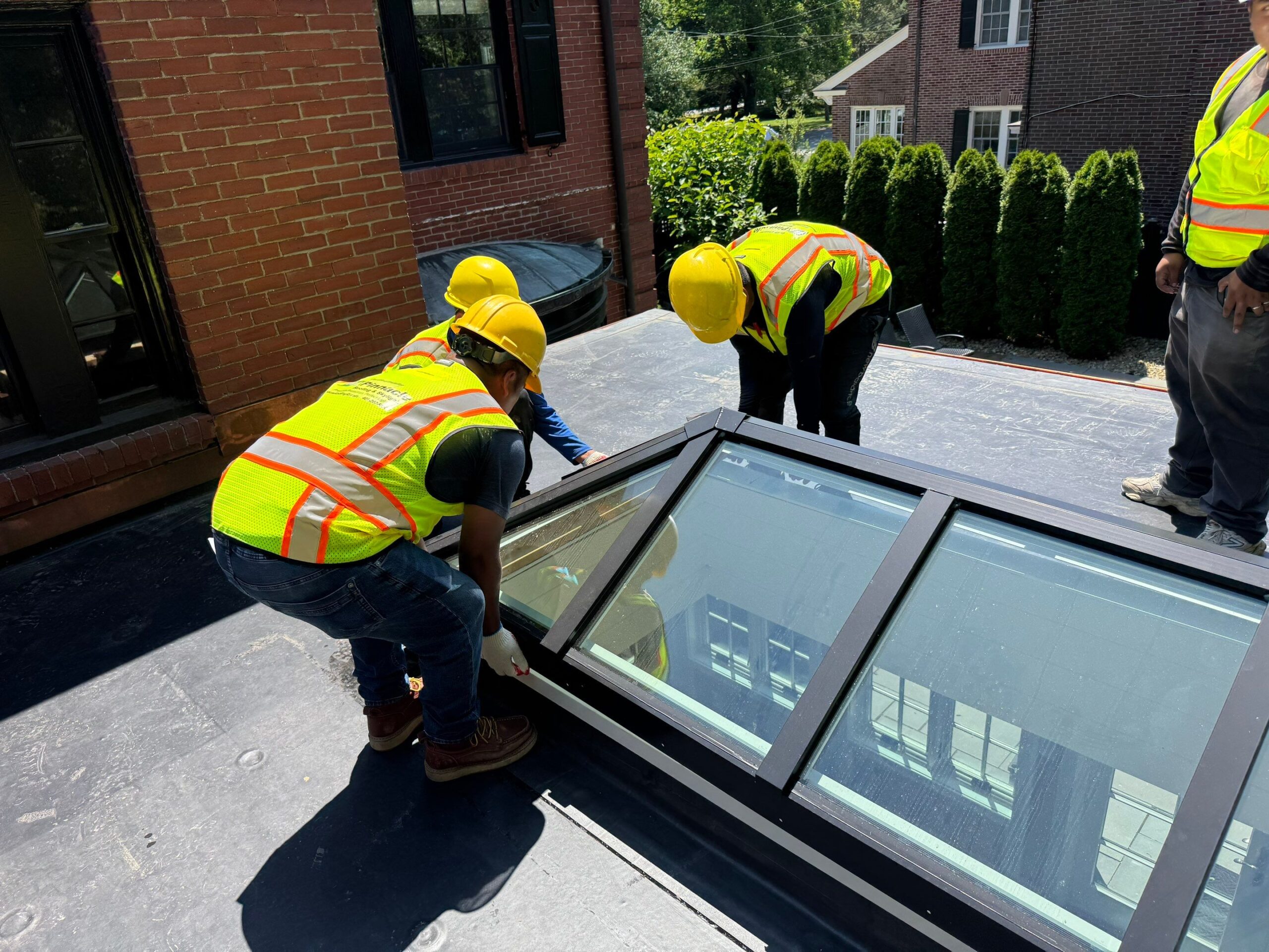 Crew installing a large VELUX metal-framed commercial skylight on a flat roof in Rhode Island