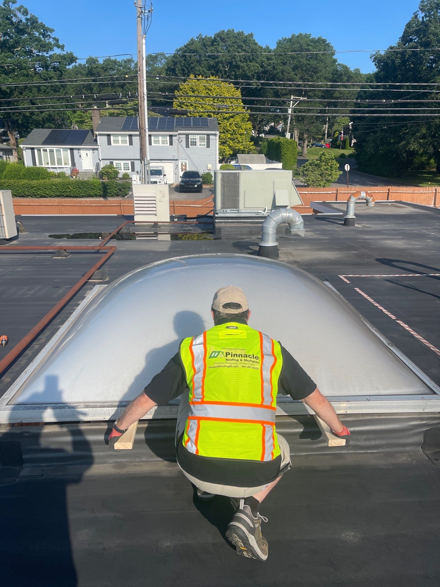 Crew installing a VELUX unit dome skylight onto a raised curb on a commercial roof in Rhode Island